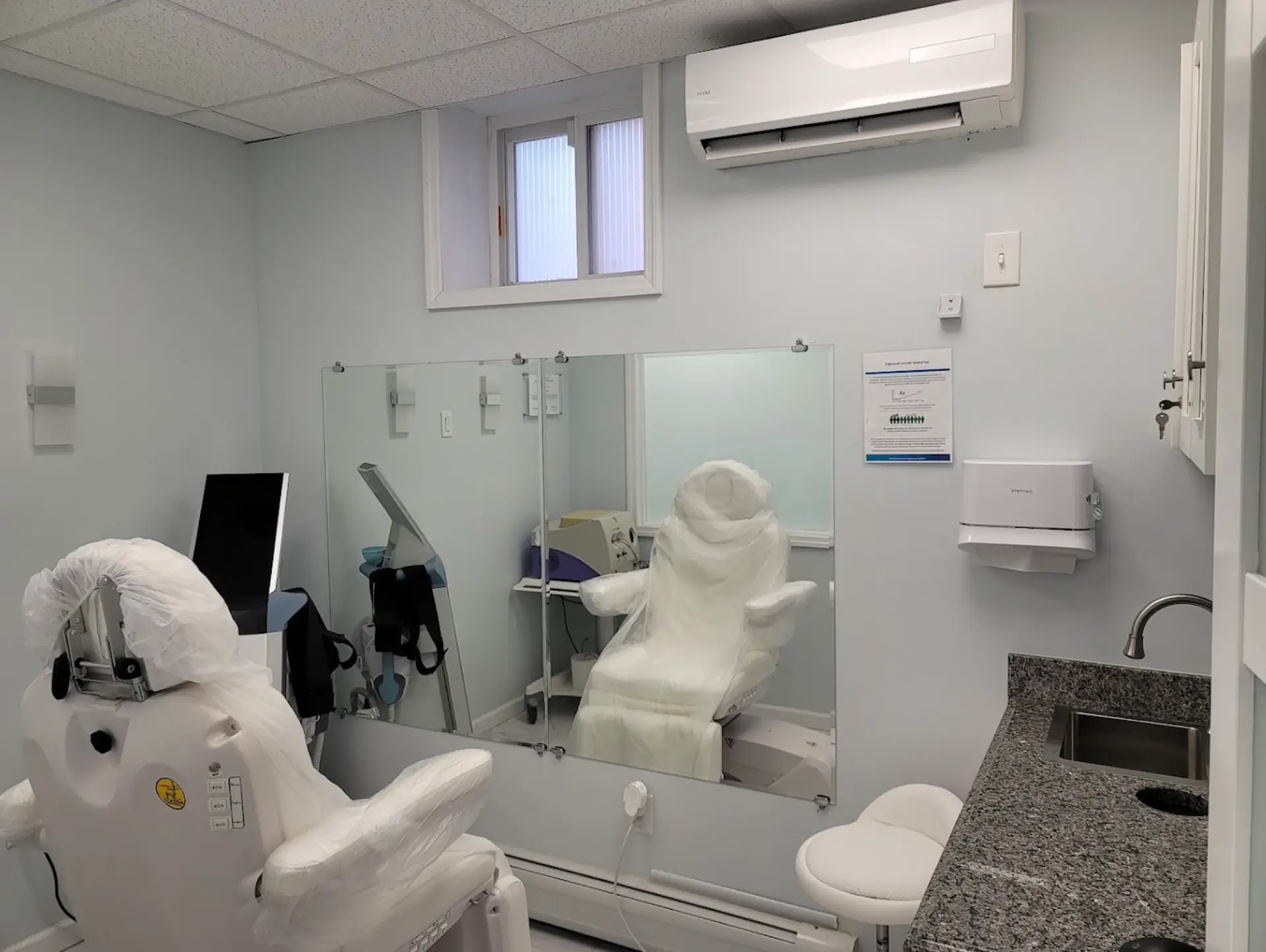 Laser and injectables treatment room with a reclining procedure chair, sink station and imaging screen